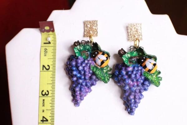 A pair of earrings with grapes and a ruler