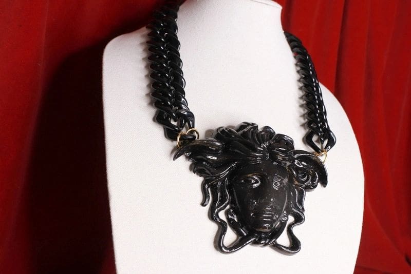 A black necklace with a medusa head on it