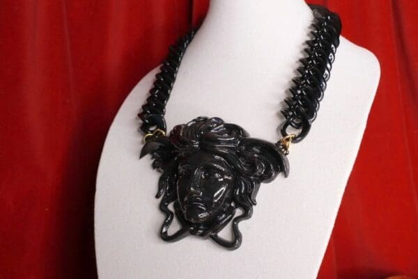 A black necklace with an medusa head on it.