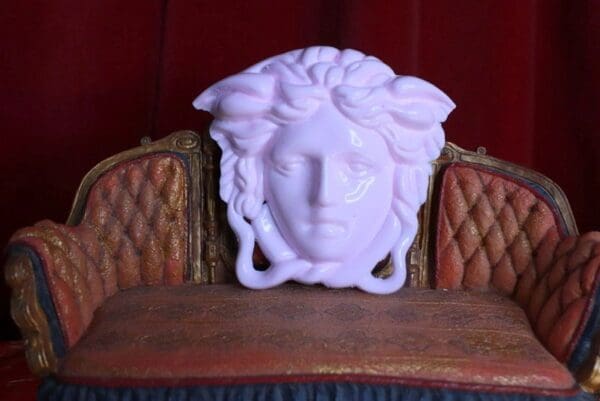 A white statue of a woman 's face on top of a chair.