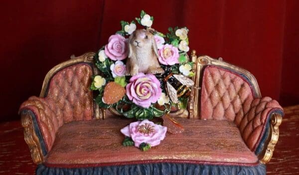 A table with two chairs and a pink flower arrangement on it.