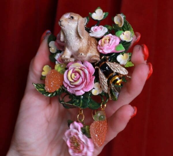 A hand holding a small bunny and flowers ornament.