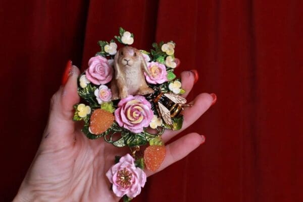 A person holding a small flower wreath with a bird on it.