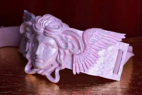 A pink statue of a winged head with a face.