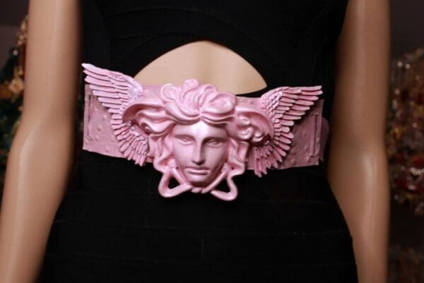 A woman wearing a pink belt with a face and wings.