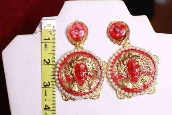 A pair of red and gold earrings on display.