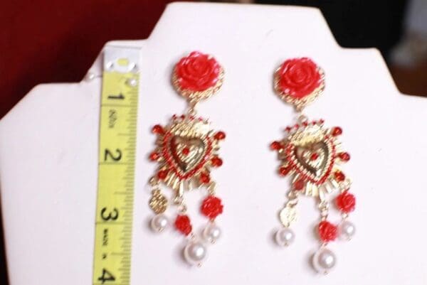 A pair of red and gold earrings with pearls.