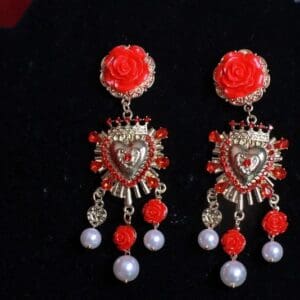 A pair of earrings with red roses and pearls.