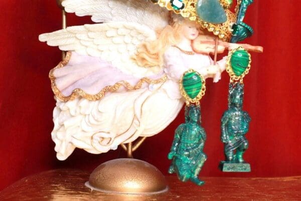 A white angel statue with green earrings on top of it.