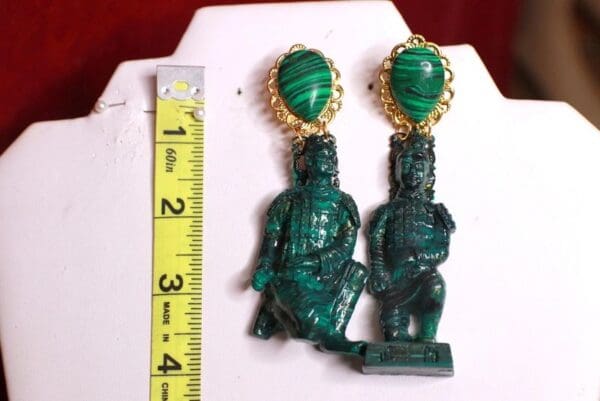 A pair of earrings with green statues on them.