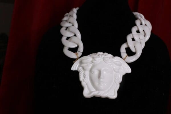 A white necklace with a face on it.