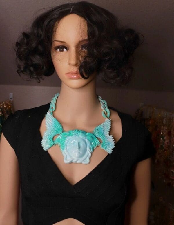 A mannequin wearing a necklace with a face on it.