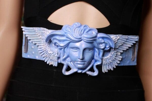 A blue winged medusa head on the side of a black hat.