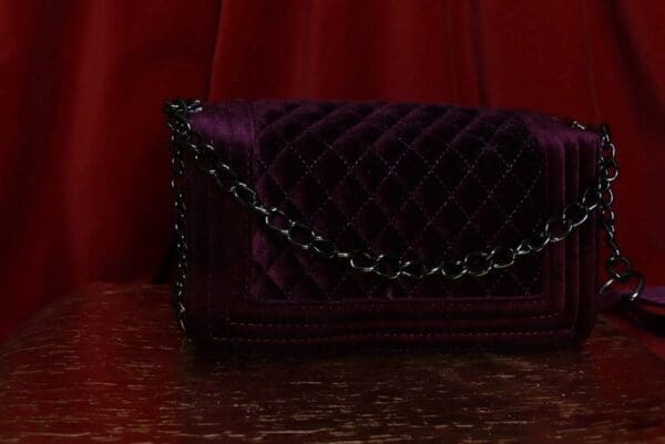 A purple purse sitting on top of a wooden table.
