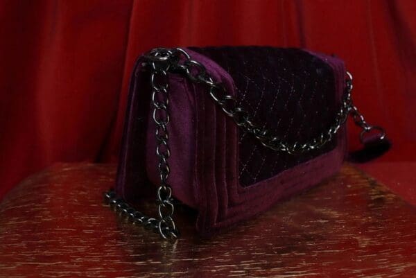 A purple purse sitting on top of a wooden floor.