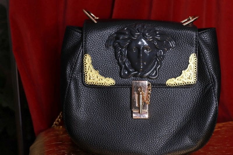 A black purse with gold accents on top of the bag.