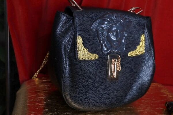 A black purse with gold accents on top of a table.