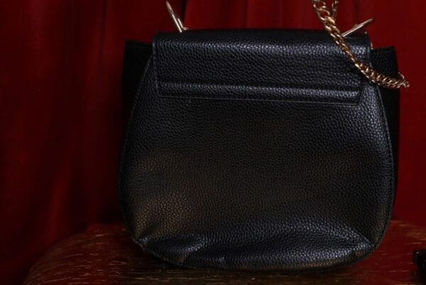A black purse sitting on top of a wooden table.