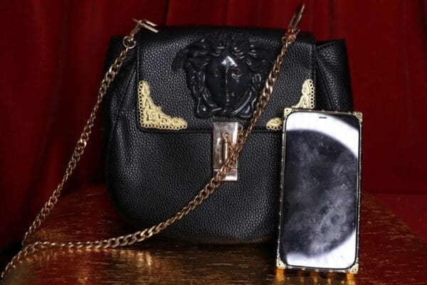 A black purse and phone sitting on top of a table.