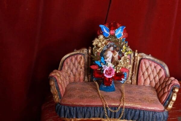 A red couch with a statue of a woman on it.