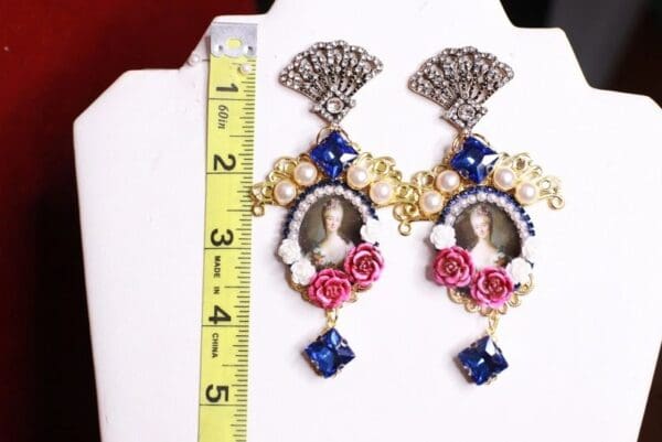 A pair of earrings with a ruler and a picture