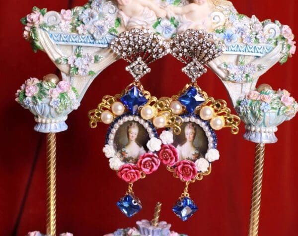 A pair of earrings with pearls and flowers on them.