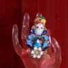 A hand holding a colorful skull ring with flowers.