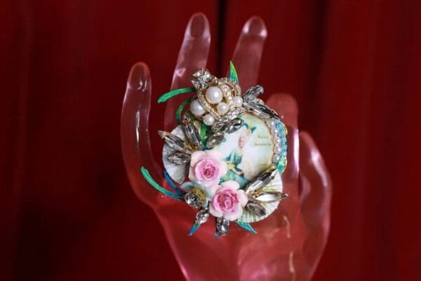 A hand holding a ring with flowers on it.