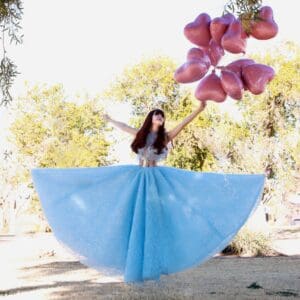 A woman in a blue dress holding balloons