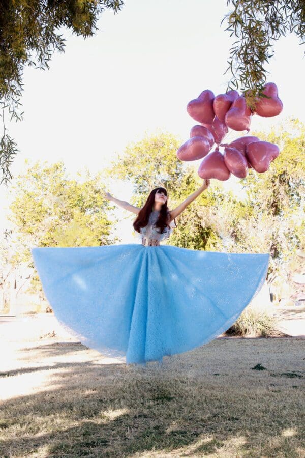 A woman in a blue dress holding balloons