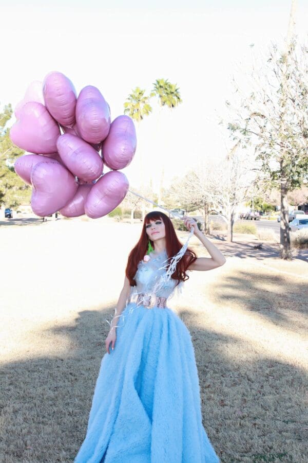 A woman in a blue dress holding balloons