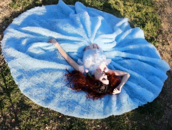 A woman laying on top of a blue blanket.