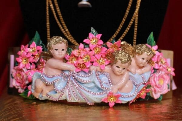A statue of four little angels with pink flowers.