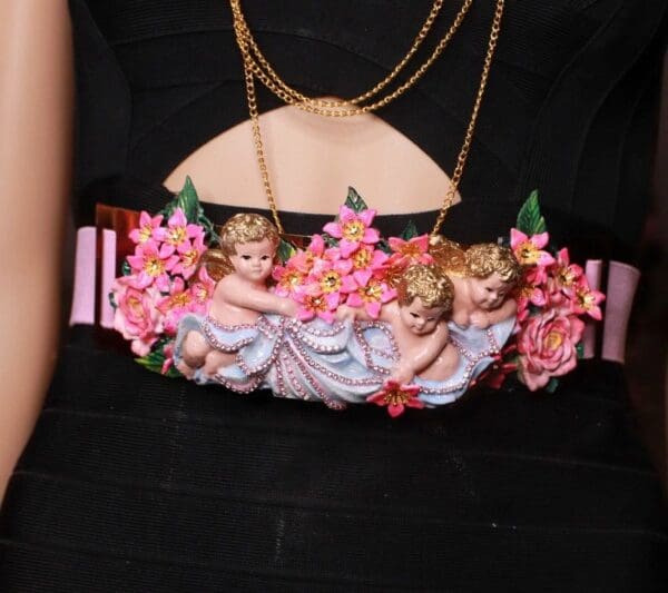 A woman wearing a belt with pink flowers and angels.