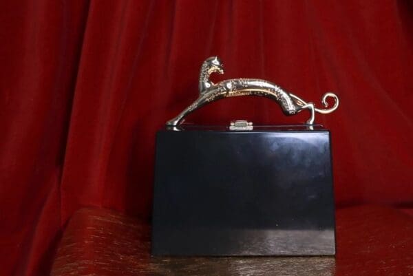 A black purse with a silver handle on top of it.