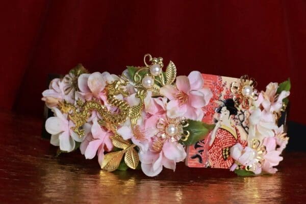 A pink flower crown with gold and pearls.