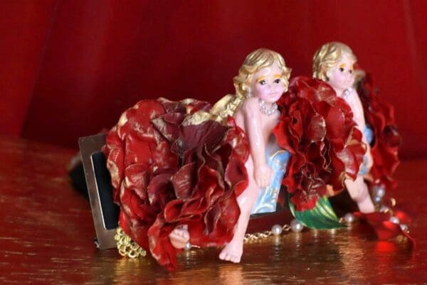 Two figurines of a girl and boy are sitting on the floor.