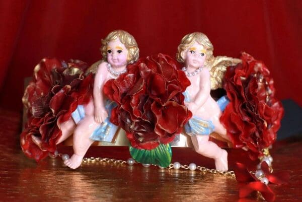 Two angels sitting on a bench with red roses.