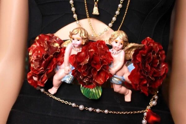 Two angels sitting on a chair with red flowers.