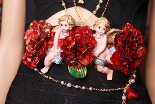 Three angels are sitting on a table holding red flowers.