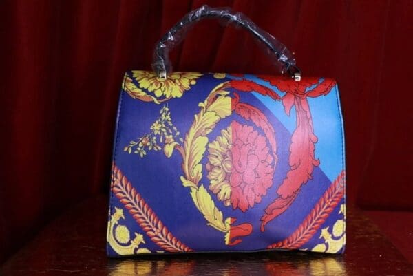 A blue purse with red and yellow designs on it.