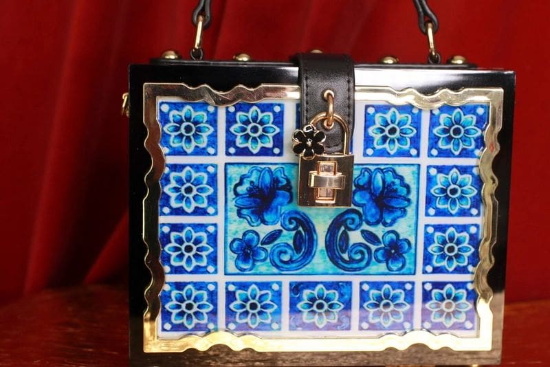 A blue and white tile purse with a lock on the side.