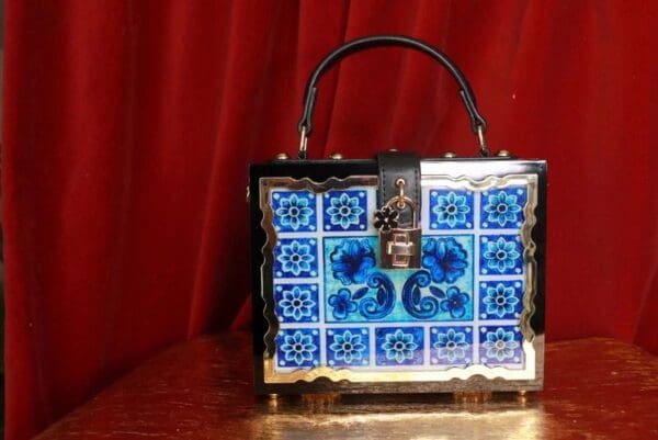 A blue and white tile purse sitting on top of a table.