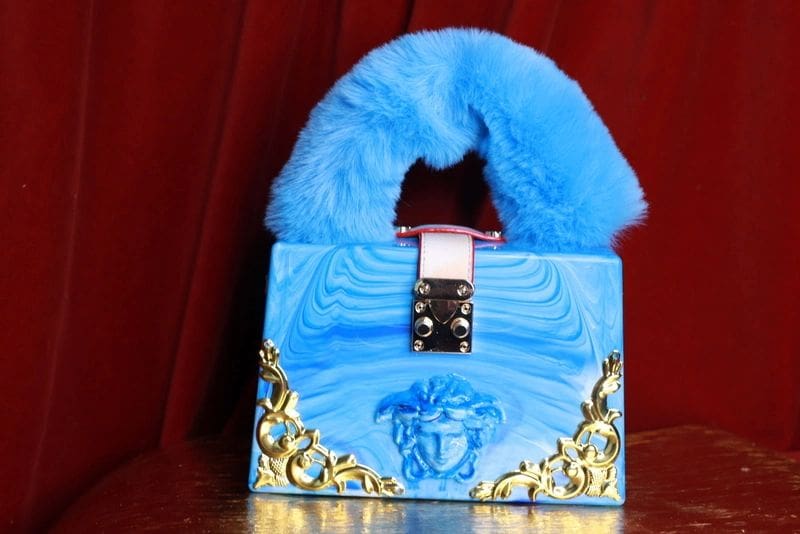 A blue purse with a fur collar on top of the table.