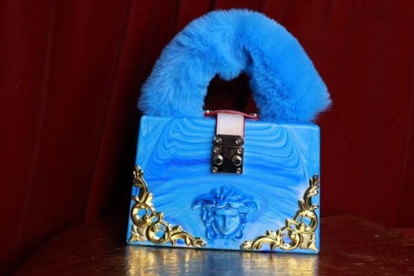 A blue purse with gold accents and a fur handle.