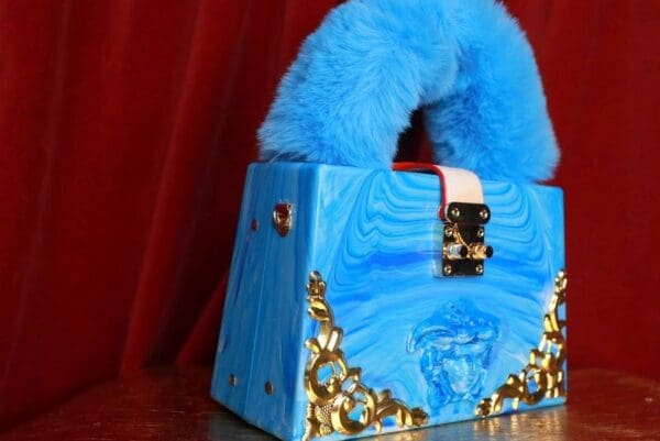 A blue purse with gold and black design on it.