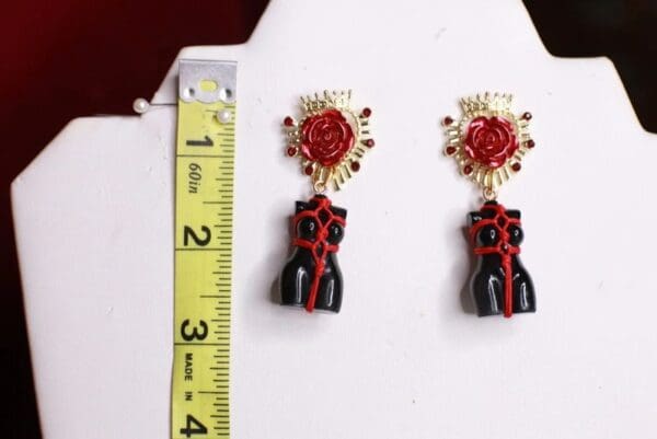 A pair of earrings with a ruler and some red roses