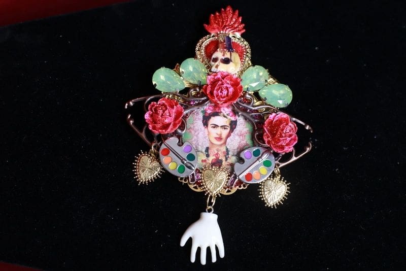 A brooch with a picture of frida kahlo and flowers.