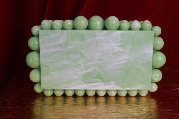 A green marble picture frame with balls around it.