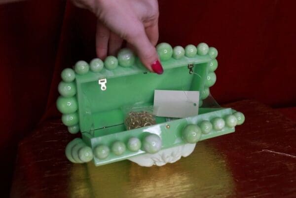 A person is holding onto the top of a green box.